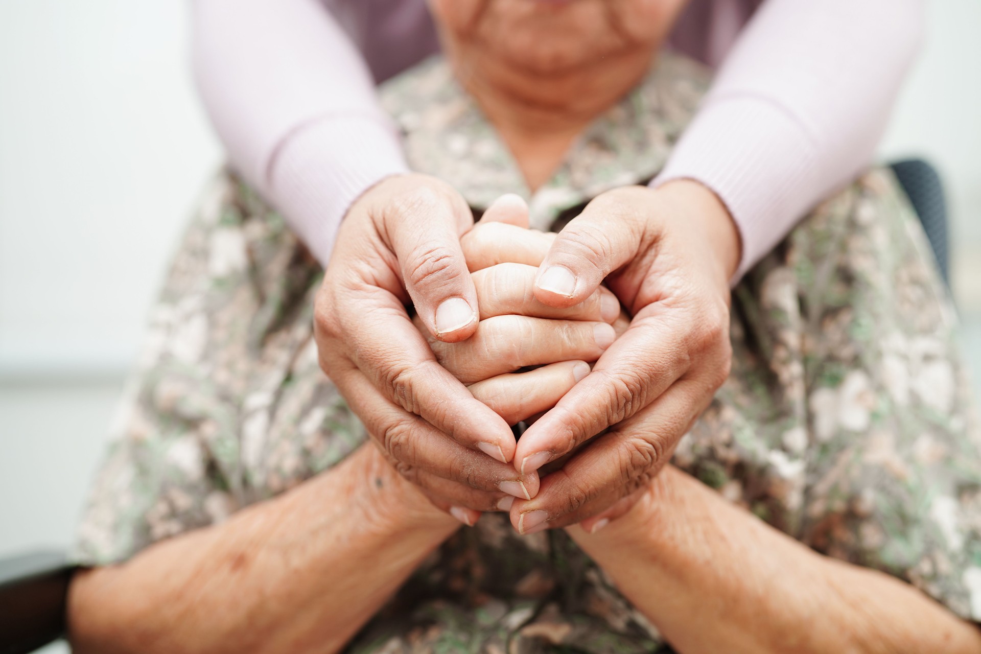 Caregiver holding hands Asian elderly woman patient, help and care at Azalea House in Altadena CA.